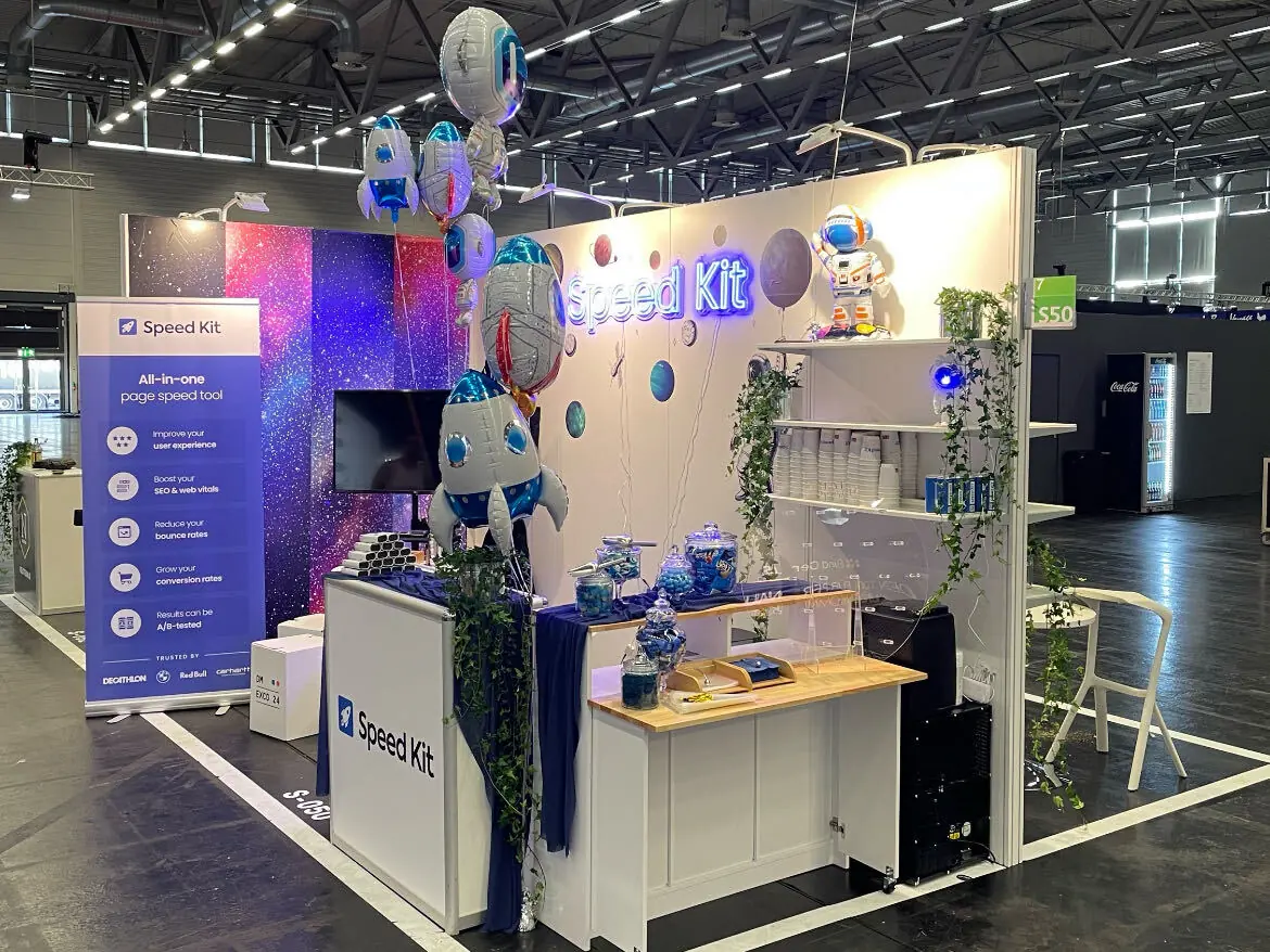 The Speed Kit stand: a white booth with a neon Speed Kit sign, rocket balloons and a counter.